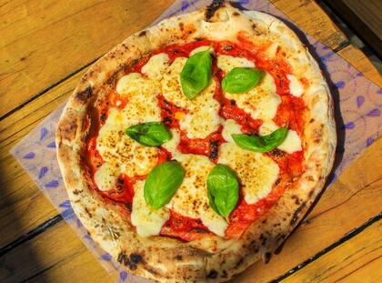 La margherita cítrica, una pizza generosamente cubierta de pomodoro, mozzarella, pesto de albahaca y rúcula.