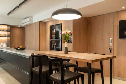 La materialidad fría de la mesada se encuentra con la calidez de la mesa en melamina de roble.