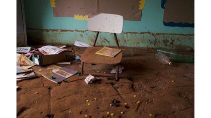 Una silla incrustada en el barro seco en el aula de una escuela destruida por el alud