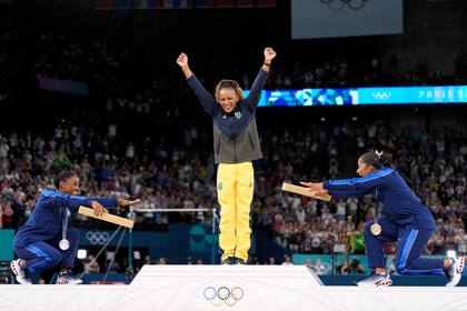 La medalllista de plata Simone Biles (izquierda) y la medallista de bronce Jordan Chiles se inclinan ante la campeona brasileña Rebeca Andrade tras ganar la medalla de oro