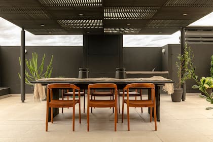 La mesa, que mide 2,60x1,20m, es de madera maciza quemada (diseño de Alejandra, realizada a medida por Lunativo): "Junto a las sillas de madera, contrastan y dan un toque rústico al sector de parrilla", cuenta la diseñadora.