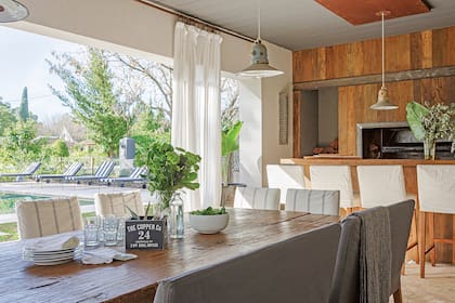 La mesa se hizo con tablones de lapacho recuperados, de tres pulgadas de espesor, sobre antiguos caballetes de hierro. Sobre ella, florero y caja negra para los cubiertos (Organizza).