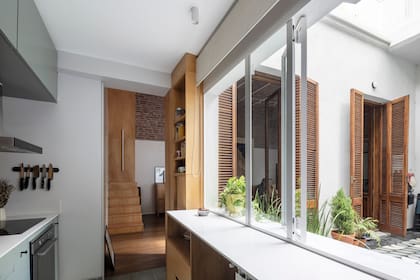 La mesada de cocina es de Silestone ‘Blanco Norte’. Hacia afuera, continúa en una angosta barra en voladizo de mármol de Carrara, que funciona también como antepecho de la ventana.