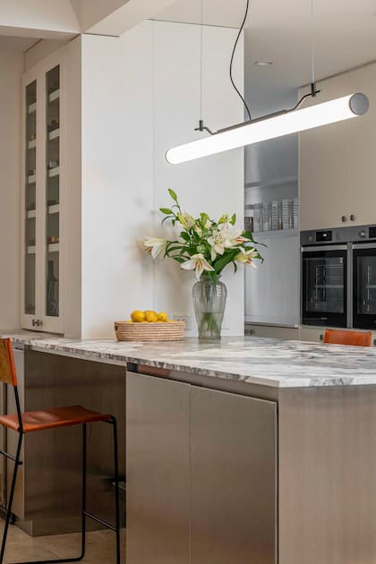 La mesada de mármol Cotte D’azur (De Stefano) une la frialdad del cuerpo de acero de la isla (Martín Mercante) con el Travertino del piso.