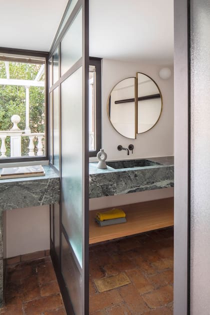 La mesada de mármol verde “corta” la mampara para cumplir distintas funciones a uno y otro lado.