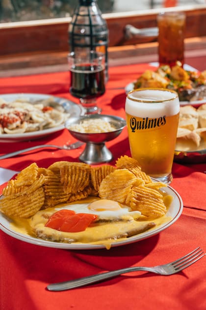 La milanesa especial Balcarce (gratinada con queso, morrón, huevo frito y papas rejilla) es el plato principal emblemático del bodegón