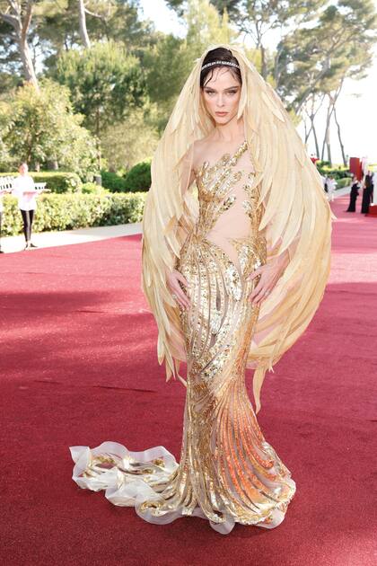 La modelo canadiense Coco Rocha con un traje semitrasparente con detalles dorados y una capa de plumas de la colección primavera/verano 2024 de Yanina Couture.