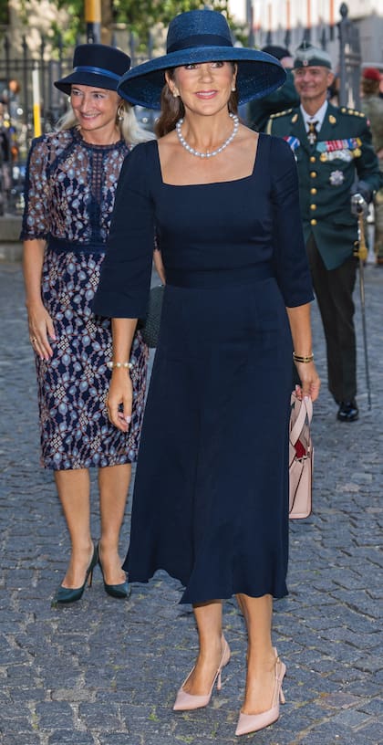 La monarca, que optó por vestido de Jane Lewis Atelier, tacos Gianvito Rossi, cartera Max Mara y collar de perlas de Dulong Fine Jewelry, llega "escoltada" por su secretaria privada Henriette Ellermann-Kingombe.