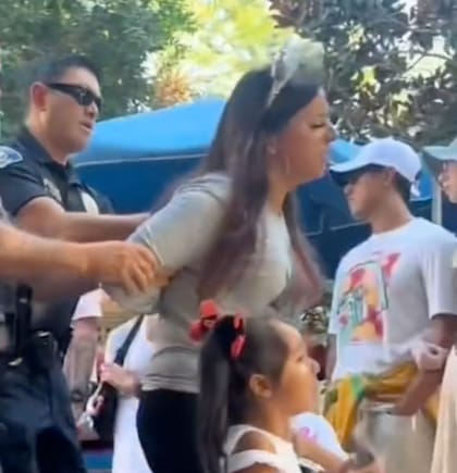 La mujer es escoltada fuera del recinto por dos oficiales de la ciudad