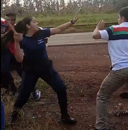 La mujer policía de la patrulla, le pega con un rebenque a uno de los jóvenes.