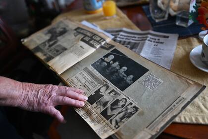 La nadadora chilena Eliana Busch, de 89 años, muestra recortes de periódicos antiguos durante la entrevista