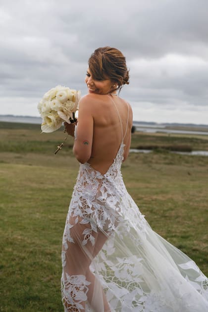 La novia, con vestido de Javier Saiach: de tul con bordados y calados Richelieu y flores en relieve; la espalda, construida con líneas triangulares, tenía un escote sensual. Llevó un collar de platino y brillantes de la joyería Crivelli; y aros a juego