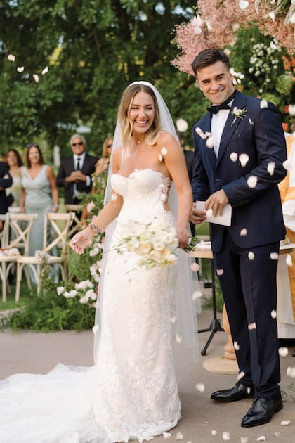 La novia llevó un traje de la diseñadora Inés di Santo que compró en San Miniato, Italia. Lo complementó con un ramo de flores frescas. El novio, en tanto, estaba de riguroso azul.