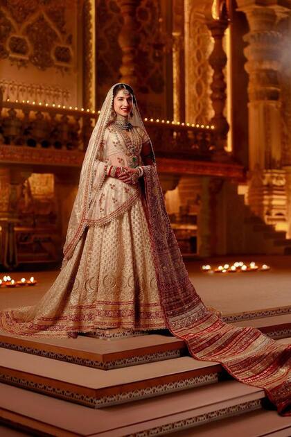La novia luce su espectacular traje de boda diseñado por
el indio Abu Jani Sandeep Khosla. Un conjunto de tres piezas: la lehenga real, un top
de mangas cortas y una dupatta de hombro bordada (una prenda similar a un chal).
El traje, de terminación brillante, estaba trabajado a mano con detalles florales y
decorado con piedras, lentejuelas y toques de seda roja.