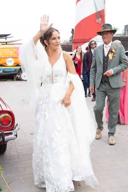 La novia saluda con el brazo en alto a sus amigos y familiares que la esperaban para acompañarla en su gran día.