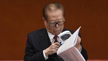 El ex presidente de China, Jiang Zemin, utiliza una lupa para leer el guión de un discurso mientras espera la apertura del Congreso del Partido Comunista Chino en el Gran Salón del Pueblo