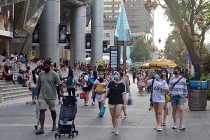 La Orchard Road del distrito comercial de Singapur llena de gente que luce barbijos en foto del 28 de noviembre del 2021. Singapur decidió empezar a vivir con el coronavirus tras una intensa campaña de vacunación que evita contagios graves. (AP Photo/Annabelle Liang)