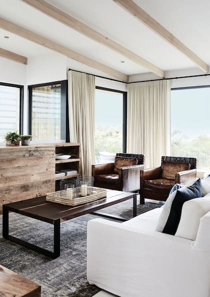 La paleta maneja tres colores: blanco, azul en algunos textiles y el contraste potente del marrón en tapizados de cuero y sólidos muebles de pinotea reciclada.