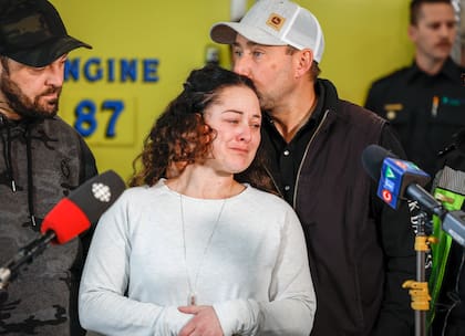 La paramédica Jayme Erickson, quien fue llamada para asistir en un accidente y no sabía que intentaba salvar a su propia hija, es consolada por su esposo Sean Erickson mientras habla con la prensa en Airdrie, Alberta, el artes 22 de noviembre de 2022. (Jeff McIntosh/The Canadian Press via AP)