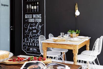 La pared del comedor diario se revistió con pintura de pizarrón y tiene un motivo gráfico (Todo con Tiza) enmarcando los estantes para el vino. Lámpara de pared, mesa con tapa de mármol (ambos, Lodd) y sillas ‘Eiffel’ (desillas.com).