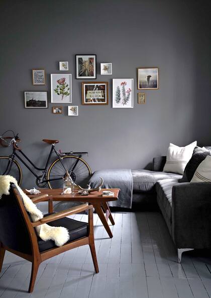 La pared gris plomo es como un gran bastidor para las láminas botánicas de Vicki Thomas, fotos de viajes compartidos y otras en sepia, tomadas por los abuelos de Janine.