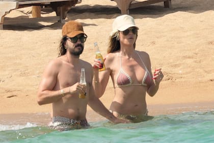 La pareja brinda por su amor con dos cervezas mientras se refresca en el mar