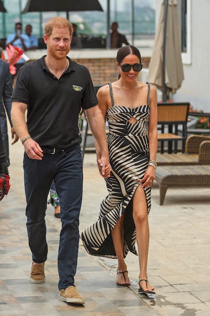 La pareja, sonriente y de la mano, llegando el sábado 11 al partido de vóley entre el jefe de Estado Mayor de Defensa y el Nigeria Unconquered, la organización benéfica que trabaja con la Fundación de los Juegos Invictus. Para este encuentro, Meghan eligió un diseño con hojas de palmera en blanco y negro de Johanna Ortiz y unas sandalias de Emme Parsons, que ya había usado en otras ocasiones.