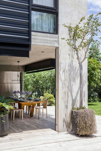 La parrilla tiene un frente ciego de acero inoxidable, un acento diferente en la materialidad general. Sillas, mesa de pino canadiense y lámpara de hierro (todo de Hugo Tonti). En los paneles de chapa sujetaron toldos (Roll Up) para extender el reparo.