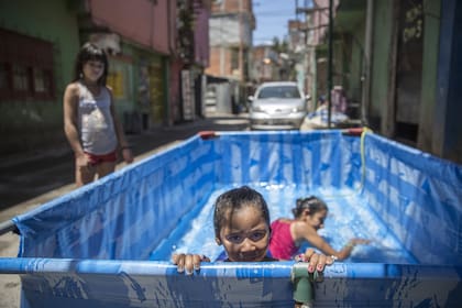La Pelopincho en pleno pasillo de la villa 31. Acacia y sus hermanos, en la pileta que armaron frente a su casa