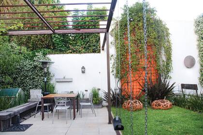 La pérgola de hierro tamiza el sol del norte. El espacio alberga la parrilla, hamacas, la huerta y el comedor.