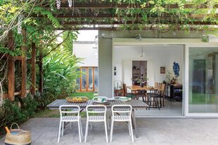 La pérgola, que se cubre de frescas glicinas en primavera, está suspendida sobre las medianeras y deja una vista continua desde el interior hacia el jardín.