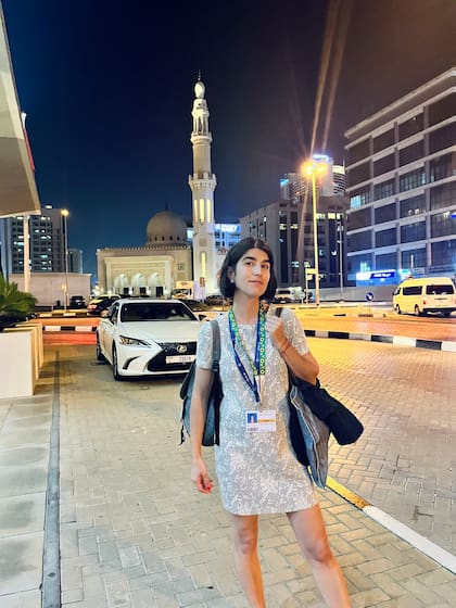 La periodista Tais Gadea Lara en la Conferencia de ONU sobre Cambio Climático de 2023, en Dubai, con el collar verde con girasoles que contribuye a la identificación de quien transita la enfermedad