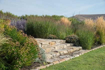 La piedra es un elemento protagónico en el conjunto formado por la casa en sí misma y los distintos trazados del jardín. Su rusticidad potencia la delicadeza de las plantas elegidas.