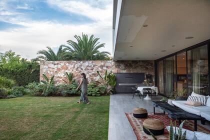 La piedra rojiza es protagonista en la arquitectura y está muy bien acompañada por una plantación que la resalta.