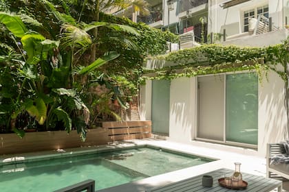 La pileta llega prácticamente hasta los ventanales, donde tiene su menor profundidad. Revestida en Piedra Bali, tiene solarium con piso atérmico.