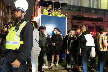 Los agentes de policía observan a los juerguistas beber y socializar en la calle en Soho