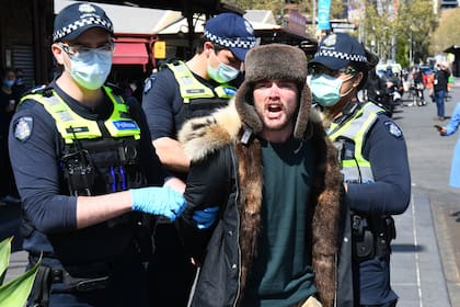 La policía detiene a un manifestante anticuarentena en el mercado Queen Victoria de Melbourne durante una manifestación, el 13 de septiembre de 2020