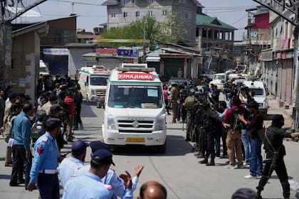 La policía hace guardia mientras ambulancias trasladan los cuerpos de turistas en Srinagar, en la Cachemira controlada por India, el 23 de abril de 2025. (AP Foto/Mukhtar Khan)