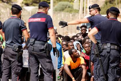 La policía italiana habla con migrantes en un centro recepción en la isla de Lampedusa, en el sur de Italia, el 16 de septiembre de 2023.