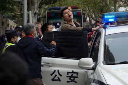 La policía se lleva a un manifestante en medio de una protesta en Shanghái