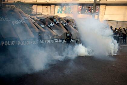 La policía se protege de gases lanzados por los manifestantes