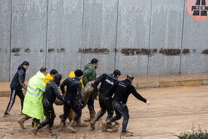 La policía y los miembros del equipo de rescate llevan el cuerpo de una persona durante las inundaciones después de las fuertes lluvias en Sanliurfa, Turquía, miércoles, 15 de marzo de 2023.