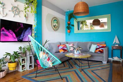 La presencia de la tele se compensó con recursos comoel sectorizado en gris debajo del espejo con marco de mimbre. A falta de rack, disimularon los cables con macetas y ladrillos huecos.