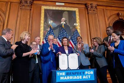 La presidenta de la Cámara de Representantes, Nancy Pelosi, acompañada por el líder de la mayoría del Senado, el senador Chuck Schumer, de Nueva York, y otros miembros del Congreso, firman la H.R. 8404, la Ley de Respeto al Matrimonio, en Capitol Hill en Washington, el jueves 8 de diciembre. (AP Photo/Andrew Harnik). (AP Photo/Andrew Harnik)