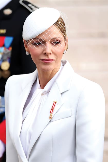 La princesa Charlene, con un conjunto de pantalón y chaqueta de Armani con
tocado con red en blanco, uno de los colores de Mónaco