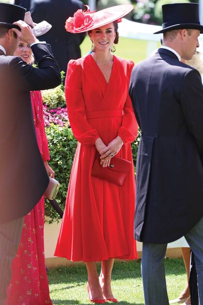 La princesa de Gales apostó por un estilismo en rojo: vestido con escote cruzado, cintura entallada y falda evasé de Alexander McQueen y sombrero Philip Treacy. Complementó con clutch de cuero Hermès (modelo Rio) stilettos Jennifer Chamandi y pendientes de Sézane.