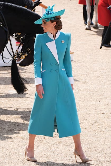 La princesa de Gales con un abrigo-vestido diseñado por Catherine Walker, quien también fue una de las modistas favoritas de su suegra, Lady Di. Los detalles: la capelina de Juliette Botterill, los stilettos Gianvito Rossi, el broche del regimiento de la Guardia Irlandesa y los pendientes de perlas y diamantes que pertenecieron a Isabel II.