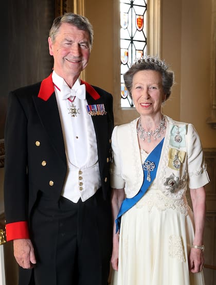 La Princesa Real y su marido, en el nuevo retrato oficial. En la foto, tomada en julio de este año, la hermana de Carlos III luce el mismo outfit que usó para su cumpleaños número 70: un vestido con chaqueta bolero con bordados. La tiara Festoon es una de las joyas más queridas: la estrenó en 1973, cuando cumplió 23 años. Junto con las insignias de la Familia Real, la Estrella del Cardo y la de la Jarretera; la banda azul simboliza la pertenencia a varias órdenes de caballería