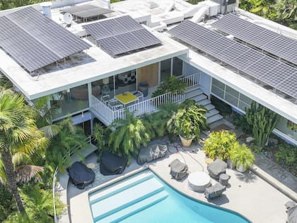 La propiedad dispone de un amplio jardín trasero con piscina, rodeada por terrazas y ventanales que conectan con el interior