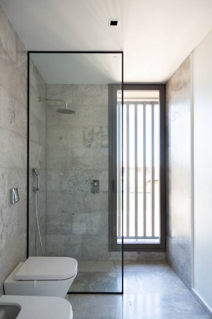 La puerta de ducha Línea Acqua, en tono negro, combina a la perfección con los revestimientos y deja pasar la luminosidad de la lucarna